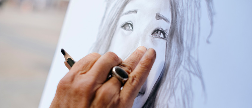 Mature hand seen drawing a portrait of a woman tourist.