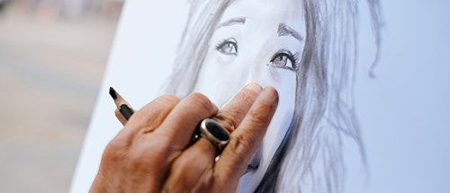 Mature hand seen drawing a portrait of a woman tourist.