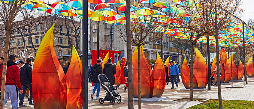 People walking under colourful umbrellas amongst sculptures of flames marking the celebration of Nauryz