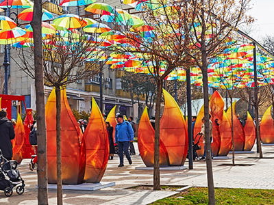 People walking under colourful umbrellas amongst sculptures of flames marking the celebration of Nauryz