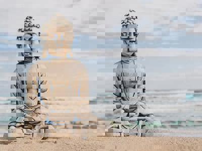 Buddha stone figure sitting on the seashore in front of the slightly rough sea