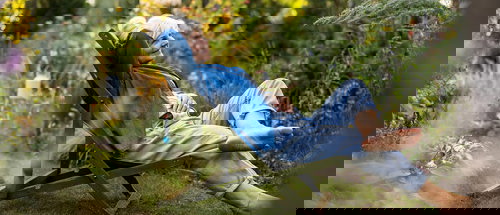 Person relaxing in a reclining chair surrounded by a lush garden, symbolizing stress-free gardening and enjoying nature in a serene outdoor setting.