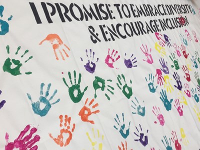 Finished mural with text: I promise to embrace diversity and encourage inclusion, with a background of lots of multicoloured handprints.
