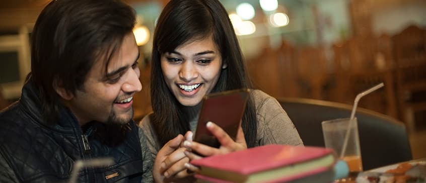 Two people sitting in a coffee shop having a conversation in Punjabi