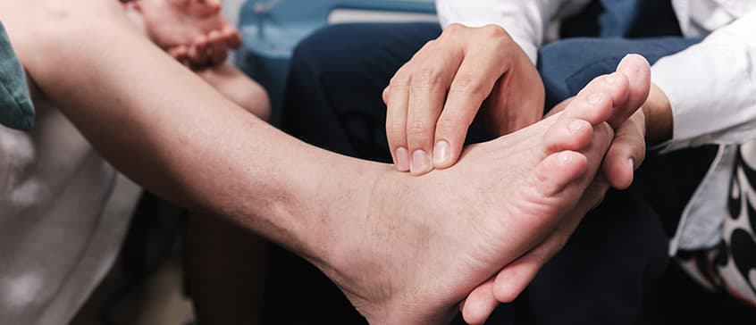 A healthcare practitioner examining a foot.