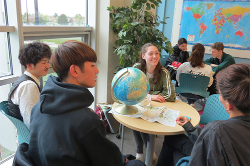 Photo of students sitting in a group practicing speaking in English.