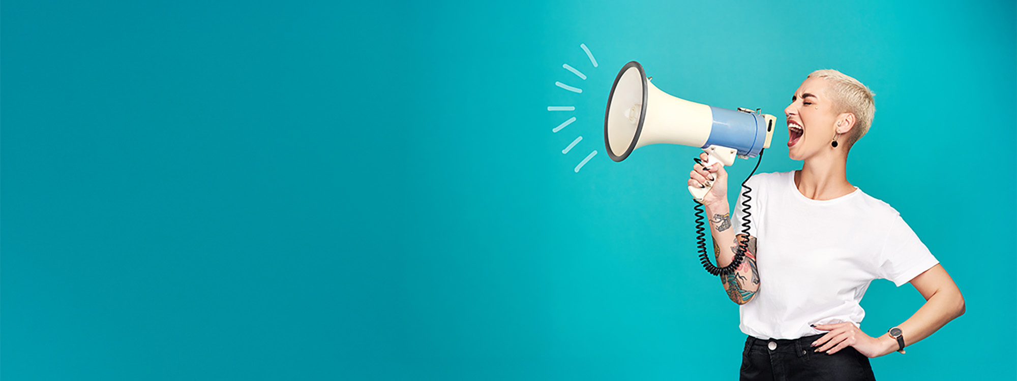 Studio shot of a young woman using a megaphone against a turquoise background.