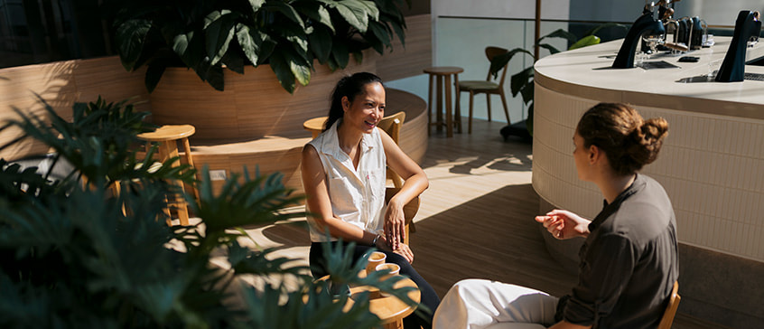 Two friends indulge in meaningful conversation at cafe. Women sitting across each other and talking while meeting at coffee shop