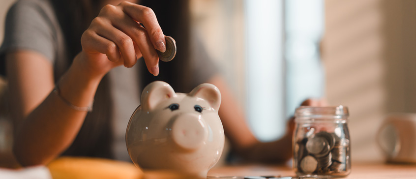 woman placing coin into piggy bank 