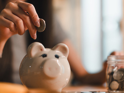 woman placing coin into piggy bank 