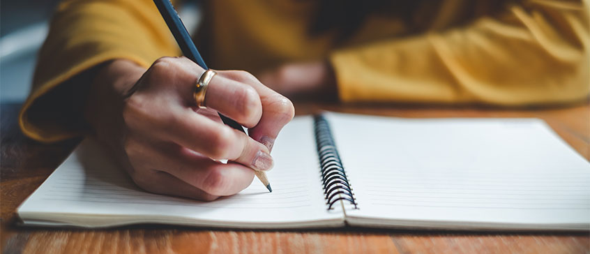 Closeup of woman writing in notebook.