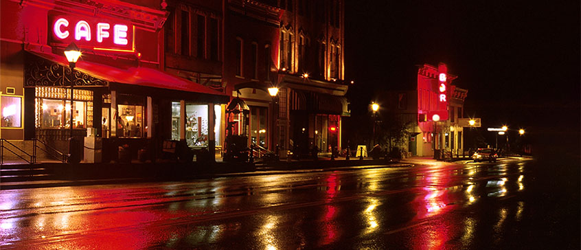 Photo of a street with shops on a rainy night.