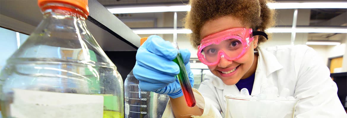 Chemistry student wearing goggles and holding a test tube.