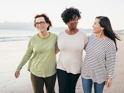 Three middle aged friends walking on a beach.