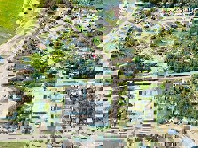 aerial view of remote buildings by a lake and riverbank