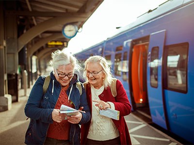 Two seniors on an adventure at a trainstation looking at a map.