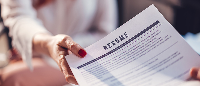 Closeup of a had giving a resume to an employer