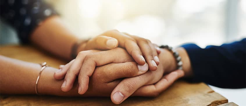 a close up photo of two people holding hands on a table