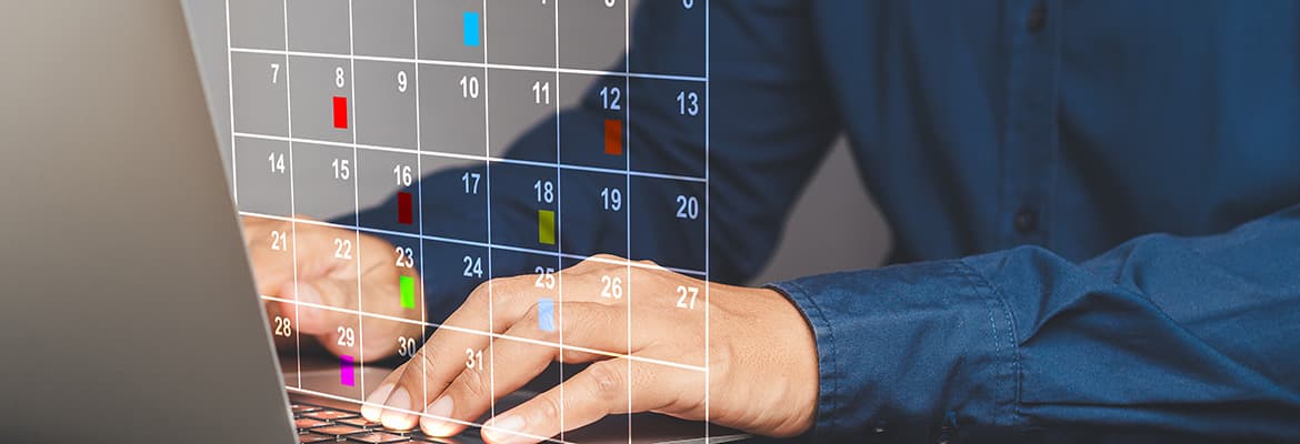 Hands typing on a laptop keyboard with a transparent calendar showing marked days flagged.