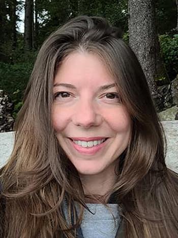 Head view of Jessica Neal with snow and a forest in the background