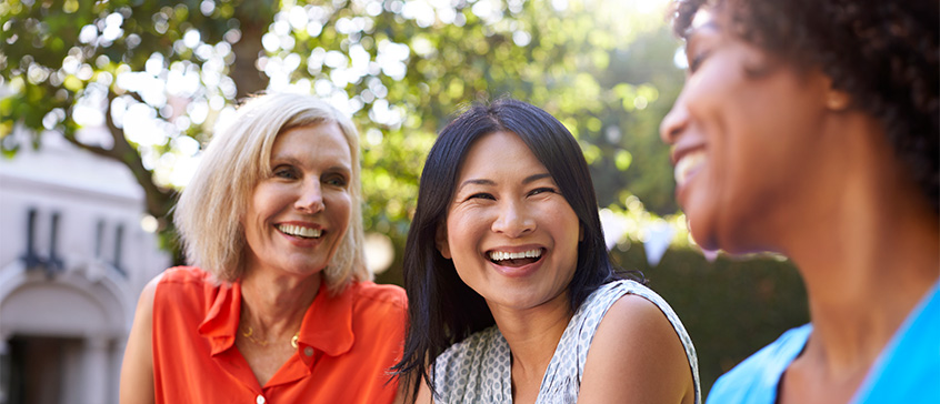 Vietnamese woman talking with two other women outdoors. 