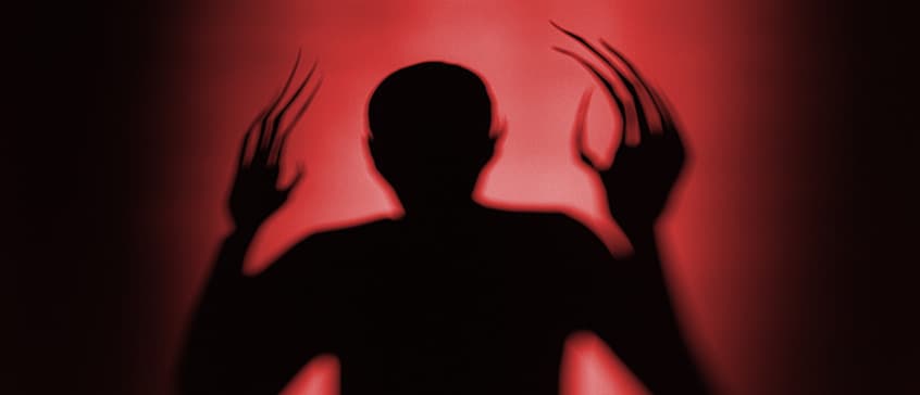 A menacing, dark silhouette of a figure with elongated, claw-like fingers raised, cast against a stark, blood-red background, evoking the iconic horror imagery associated with Nosferatu
