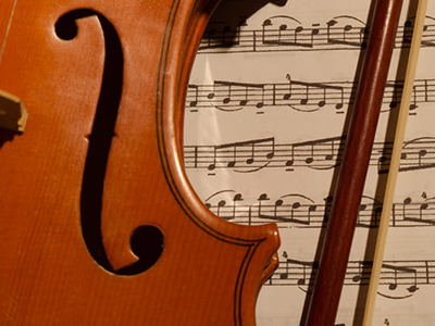 Close-up of violin and bow resting on classical sheet music, evoking the timeless tradition of traveling to experience iconic classical music performances in renowned venues worldwide