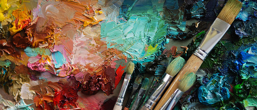 Closeup photo of paintbrushes on a  colourful canvas. 