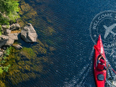 Birdseye view of a red kayak paddling off a rocky shore