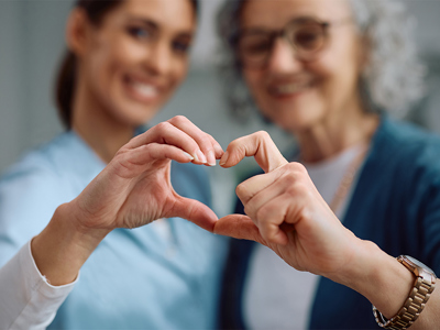 Nurse and senior holding hands to form the shape of a heart. 