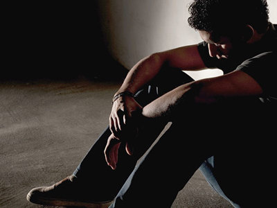 Man sitting on ground in low lighting.