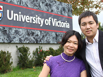 2 international students posing in front of the University of Victoria entrance sign.