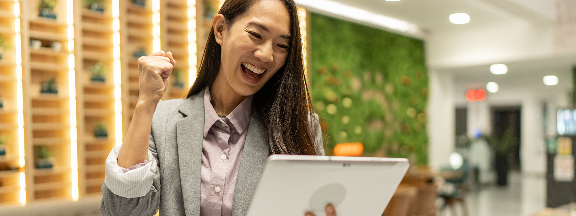 Shot of a woman cheering while using her tablet.