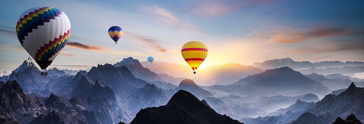 Colorful hot air balloons float above layered mountain ranges at sunrise, with soft orange and pink light illuminating misty peaks that fade into the distance, symbolizing exploration and new perspectives in learning