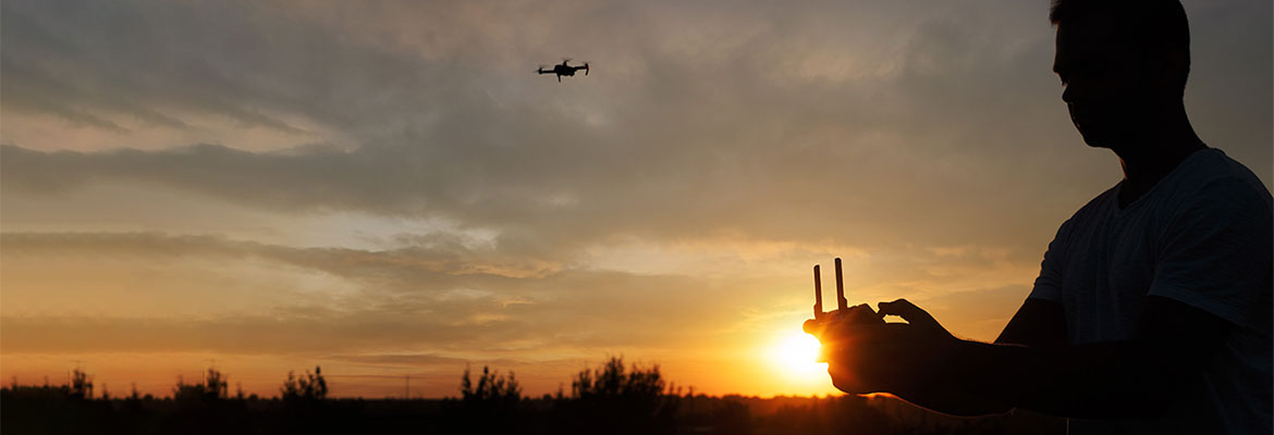 Silhouette of person flying a drone.