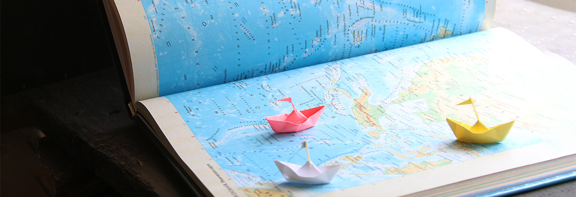 Small paper boats on a map of the world. 