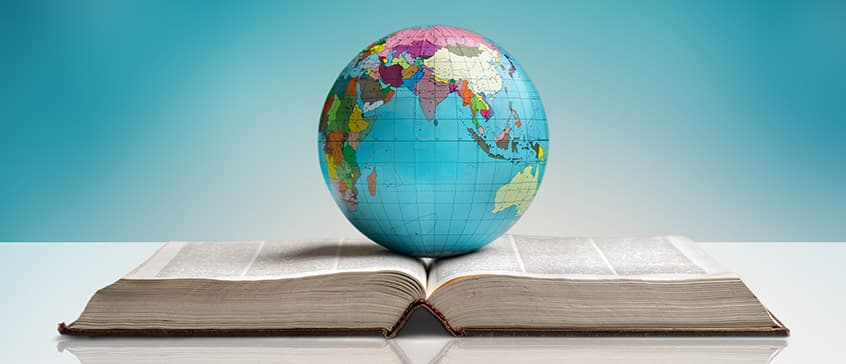 Globe of the Earth resting on an open reference book. The globe is showing the Indian ocean, India, east coast of Africa and Oceana