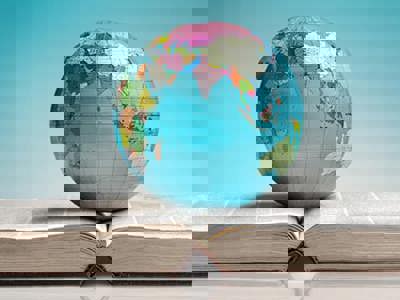 Globe of the Earth resting on an open reference book. The globe is showing the Indian ocean, India, east coast of Africa and Oceana