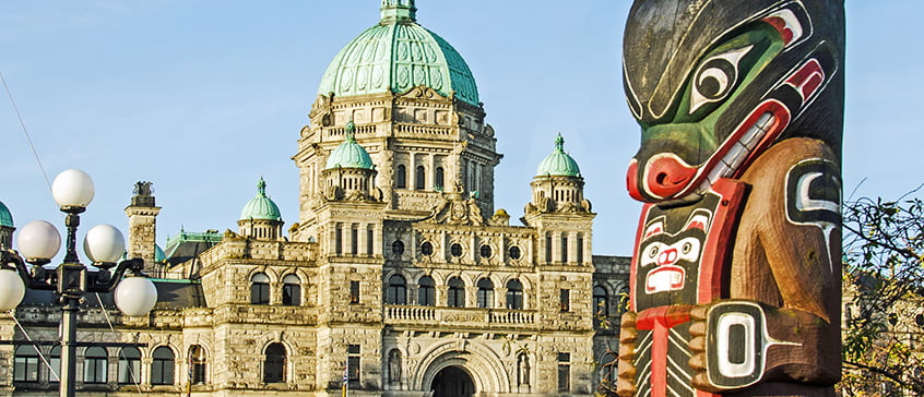 A totem pole in front of the Victoria, BC Parliament buildings
