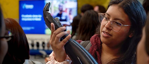 A woman holding a prosthetic arm while attending a group language course