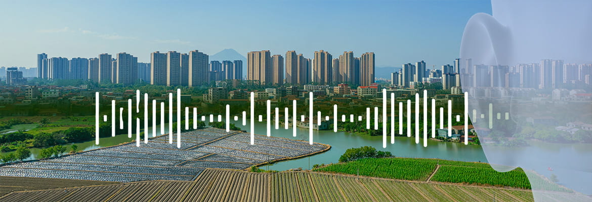 Panoramic view of a modern city skyline with high-rise residential buildings in the background, overlooking agricultural fields and farmland in the foreground, with a translucent overlay of white data visualization bars resembling an audio waveform or statistical chart, and a subtle ghosted profile of a human head on the right side, symbolizing the intersection of urban development, environmental factors, and human health analysis.