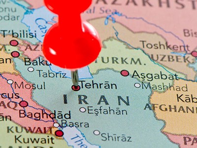Photo of a world globe with a thumbtack on Iran.