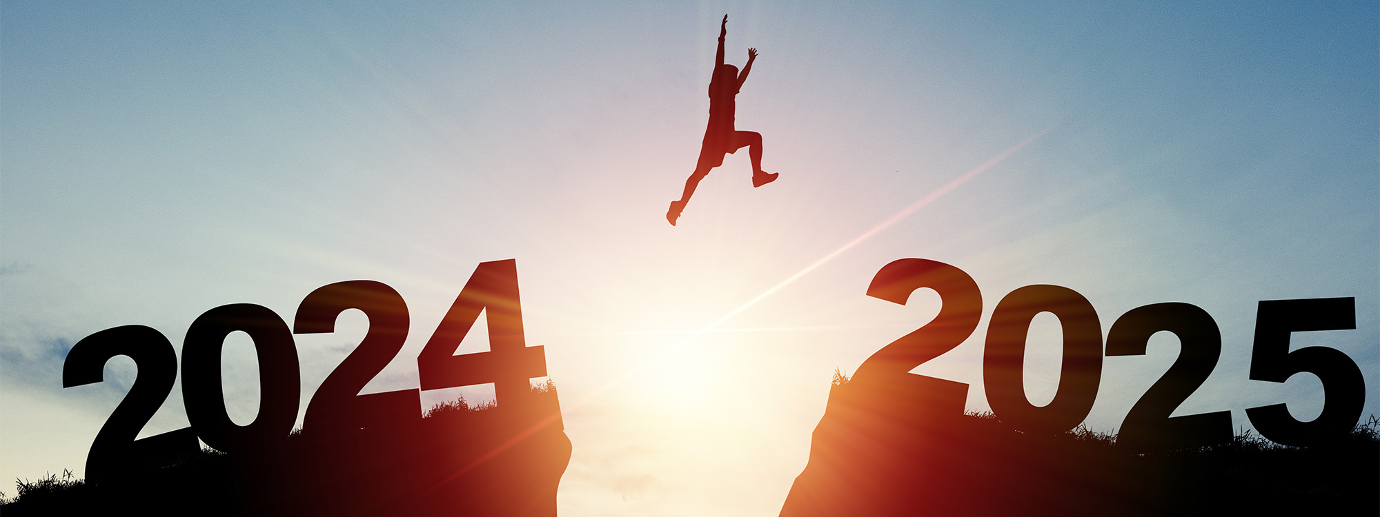 Silhouette Man jumping from 2024 cliff to 2025 cliff with cloud sky and sunlight.