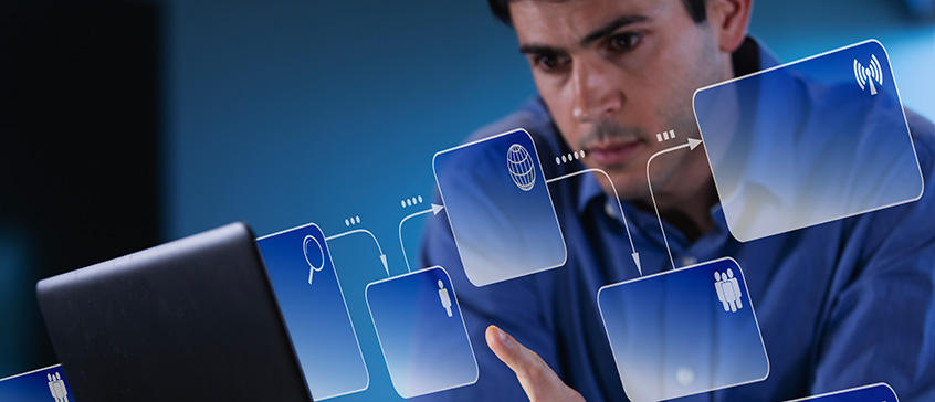 Person using a laptop with floating digital interface icons such as search, connectivity and user profiles, representing computing and information systems technology.