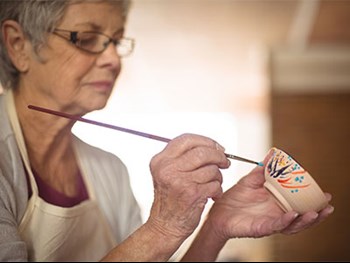 Photo of a senior citizen painting a bowl
