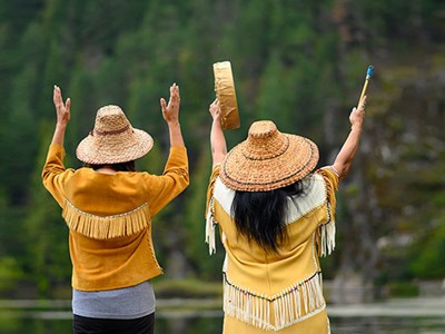 Two indigenous people doing a small ceremony at a lake.