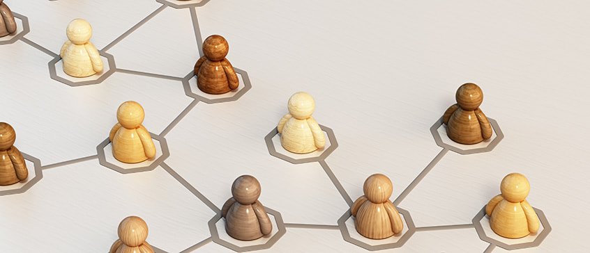 A number of wooden figures in a variety of flesh colours sitting in a networked configuration