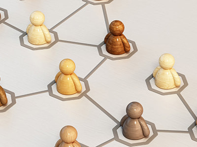 A number of wooden figures in a variety of flesh colours sitting in a networked configuration