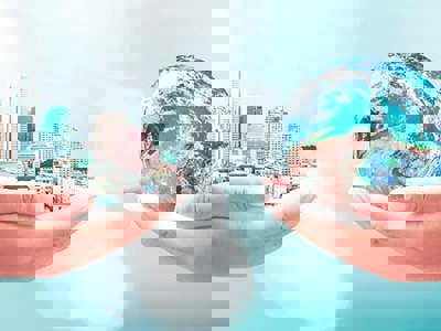 Hands holding a large city on the left with hands holding the earth on the right.