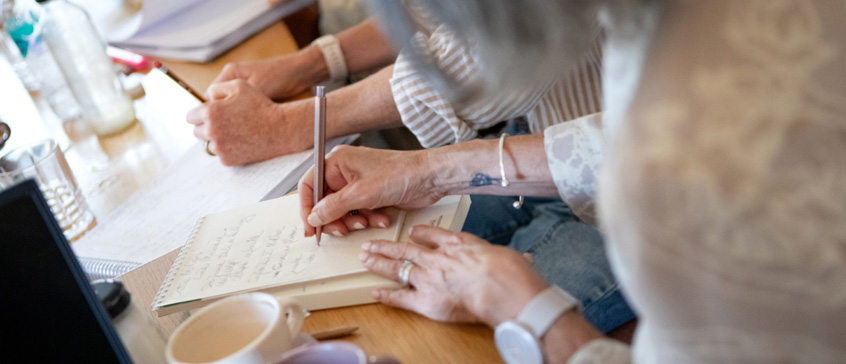 Closeup of hands writing in journals.